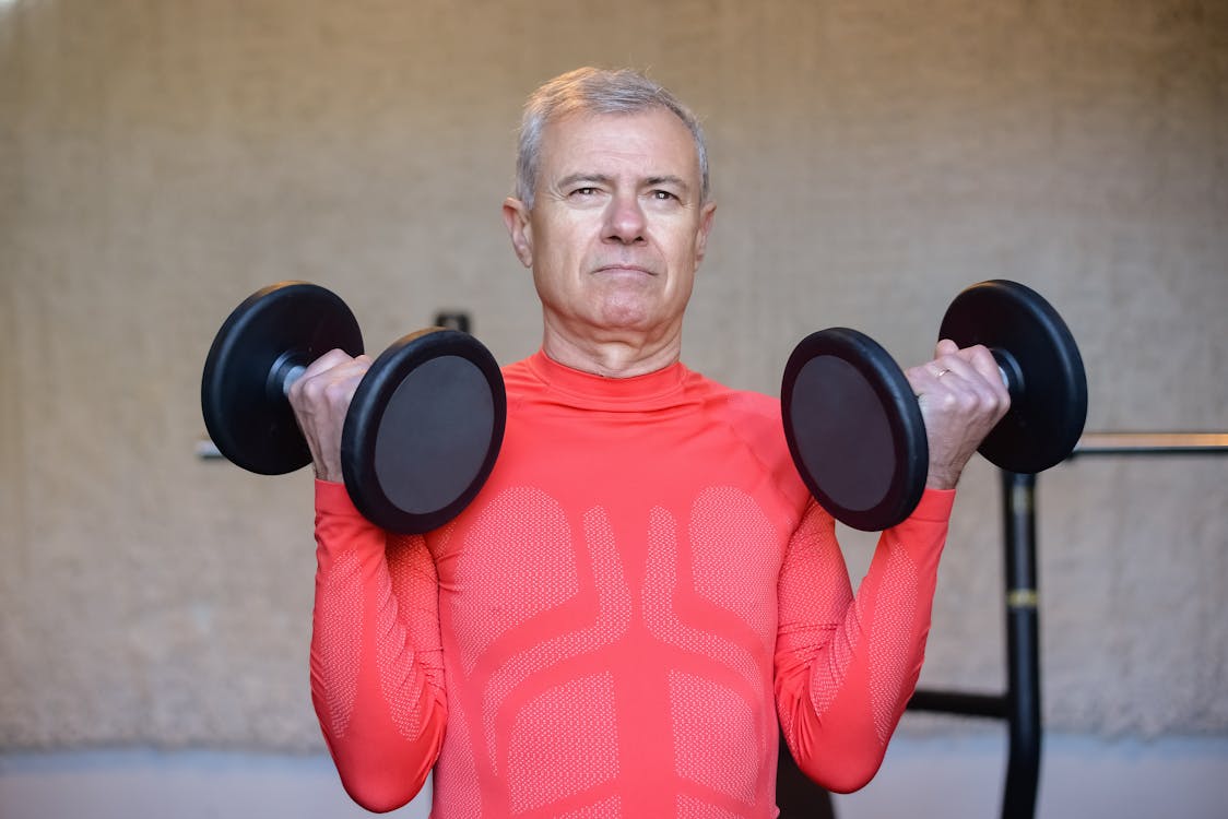 Hombre de 50 años realizando entrenamiento de fuerza con mancuernas para frenar la sarcopenia